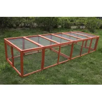 Long reddish-brown wooden animal run with wire mesh walls and segmented mesh roof on grass