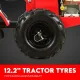 Close-up of a large black tractor-style tiller wheel with deep tread and metal retaining pin